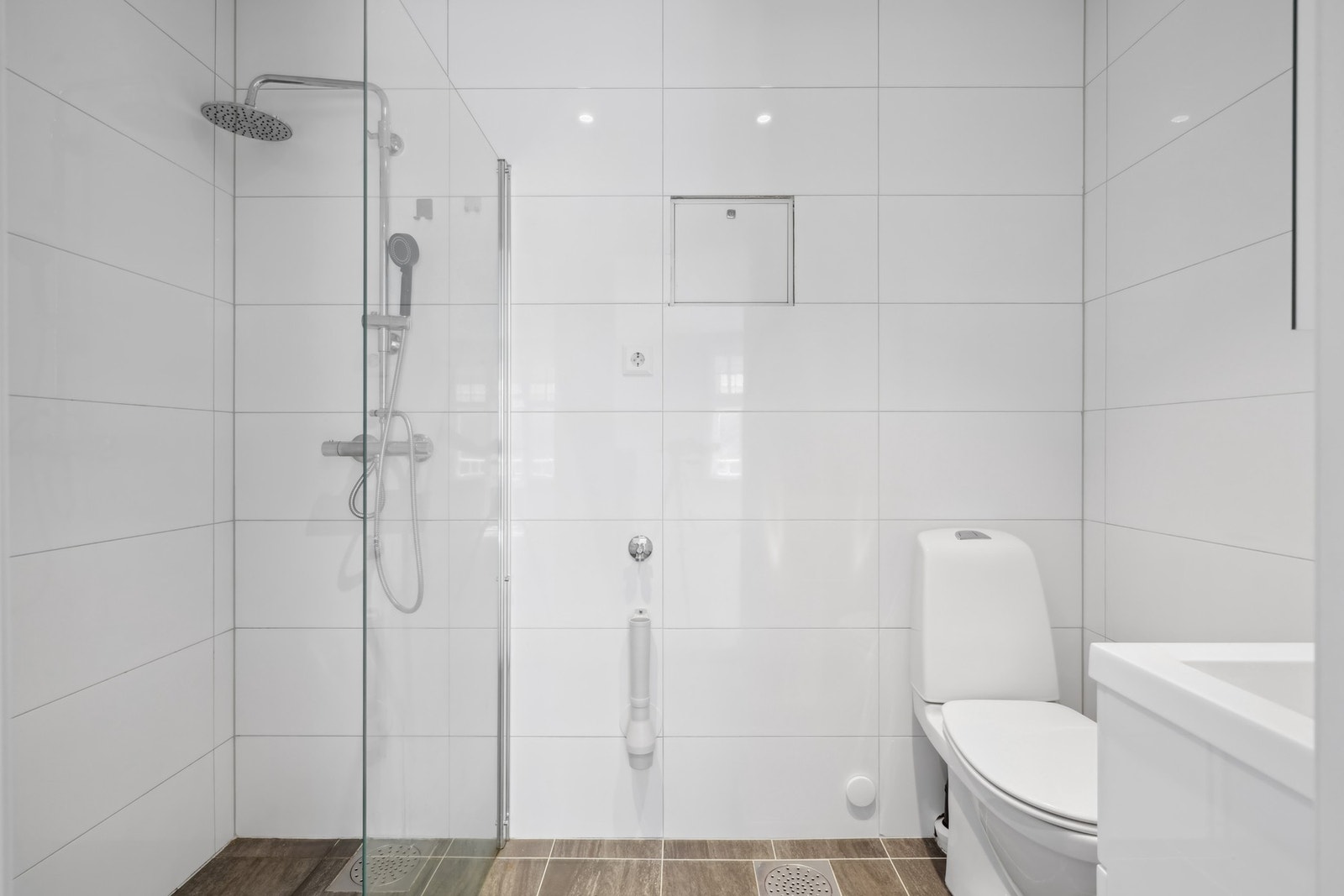 Pent helfliset bad fra 2020, med elektriske varmekabler i gulvet og dimbare ledspotter i himling. Galleribilde