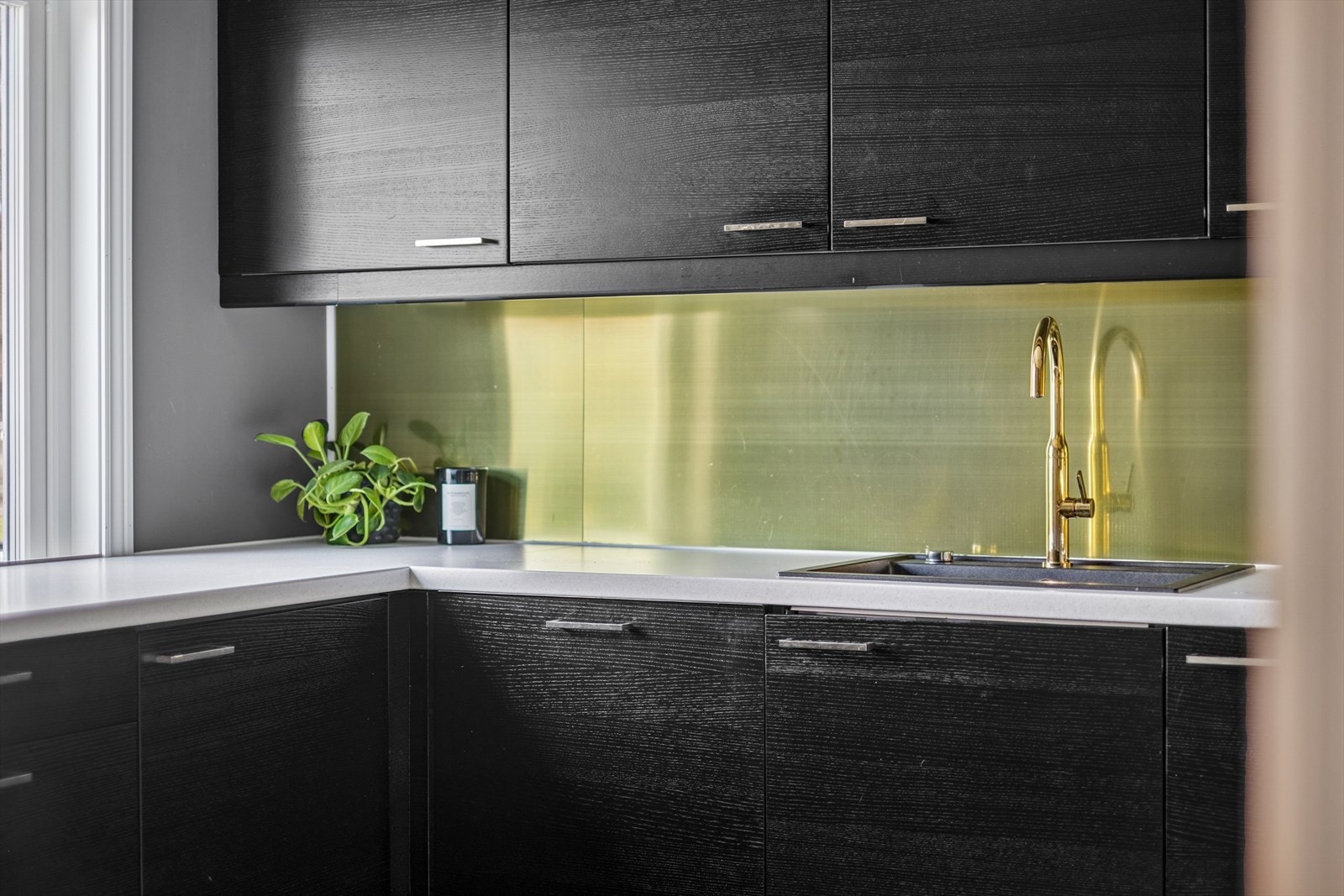 Vegg bak benkeplate har børstet messingplate, praktisk ved matlaging. Galleribilde