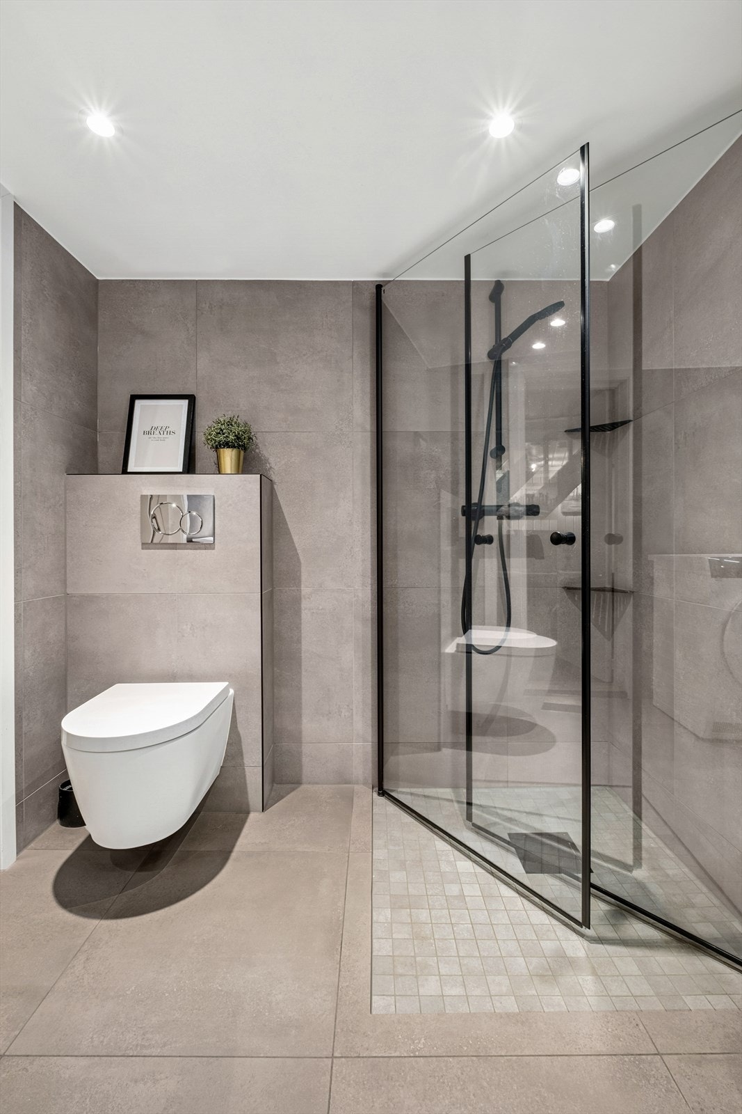 Badet er utstyrt med vegghengt toalett, dusjhjørne med glassvegger, baderominnredning med servant og speilskap, samt opplegg for vaskemaskin og tørketrommel. Galleribilde