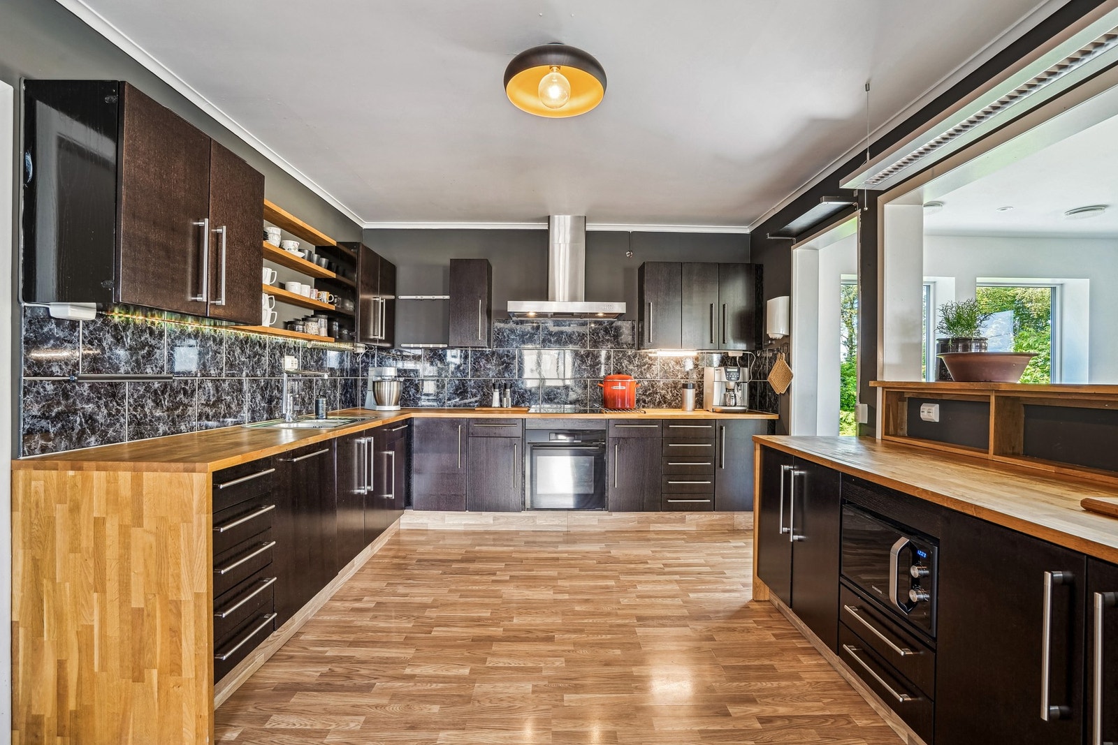 Innholdsrik innredning med mørke fronter og fliser på vegg over heltre eik benkeplate. Galleribilde