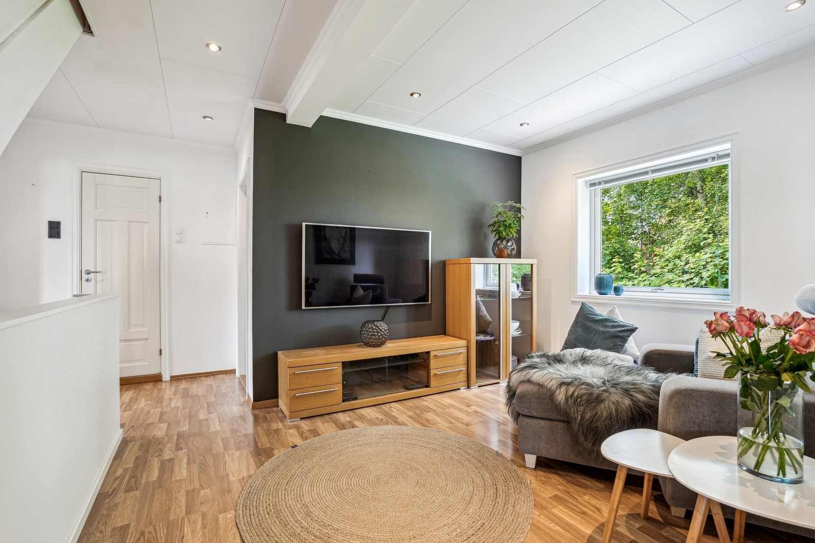 En lun stuekrok hvor grønne omgivelser utenfor møter varme toner og komfortable sitteplasser inne. Galleribilde