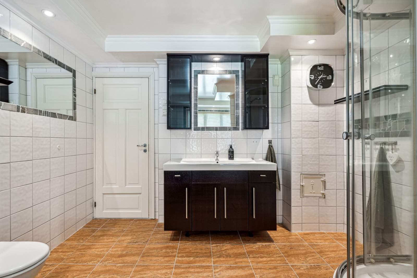 - servantinnredning med helstøpt servant, to overskap, speil integrert i flis, dusjkabinett og vegghengt toalett. Galleribilde