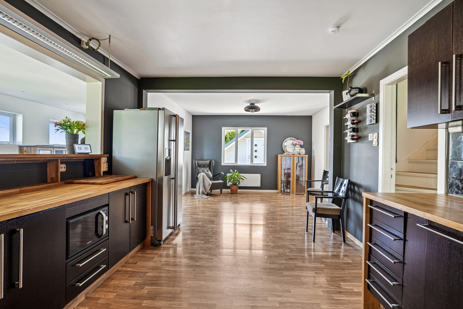 Et kjøkken som inviterer til hygge - lune trebenker, dype farger og åpent rom som flyter sømløst sammen med stuen. Galleribilde