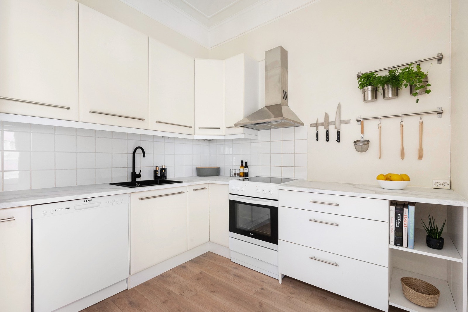 Lys kjøkkeninnredning med frittstående hvitevarer. Samtlige hvitevarer, foruten kjøleskap, medfølger handelen Galleribilde