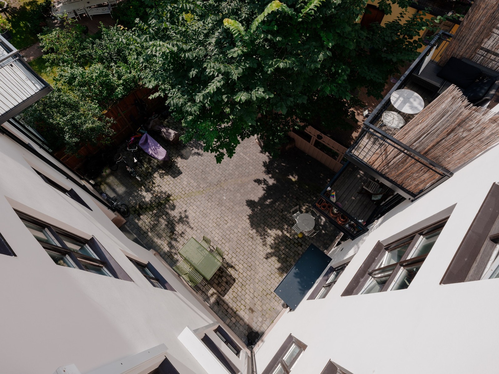 Pent opparbeidet gårdsrom med sittegrupper sykkel-/barnevognparkering og beplantning. Galleribilde