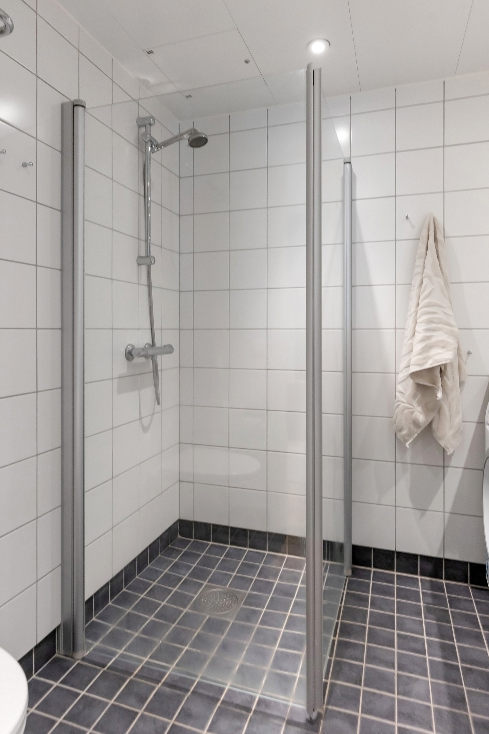 Rommet har innredning med nedfelt servant, veggmontert toalett og dusjhjørne Galleribilde