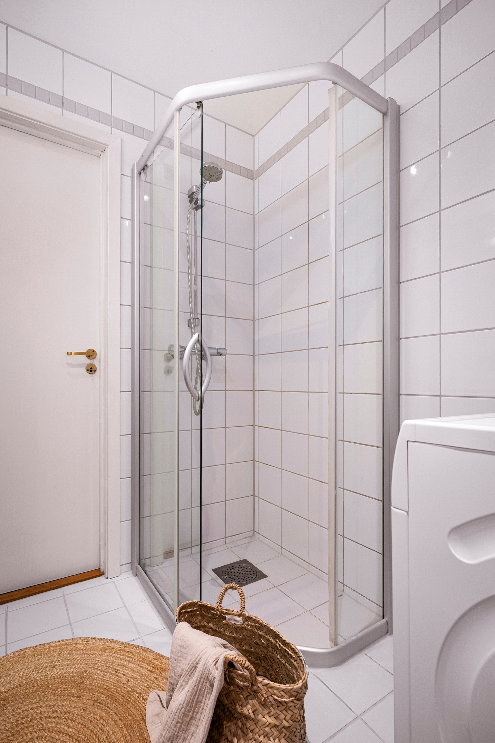 Innredningen består av en heldekkende, bred servantplate på sort skapinnredning, et fastfliset speil med belysning, et veggmontert toalett og et dusjhjørne med skyvedører i glass Galleribilde