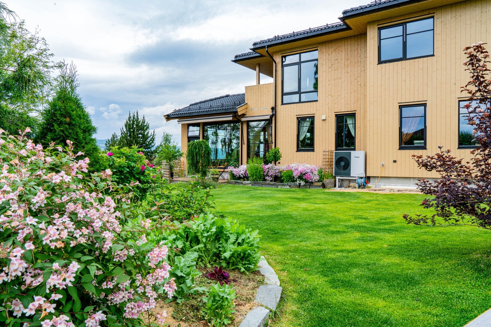 Hagen er frodig og velstelt, med vakre blomsterbed, prydbusker, frukttrær og grønne plenområder som gir rikelig med plass til både lek, avslapning og hageglede. Galleribilde