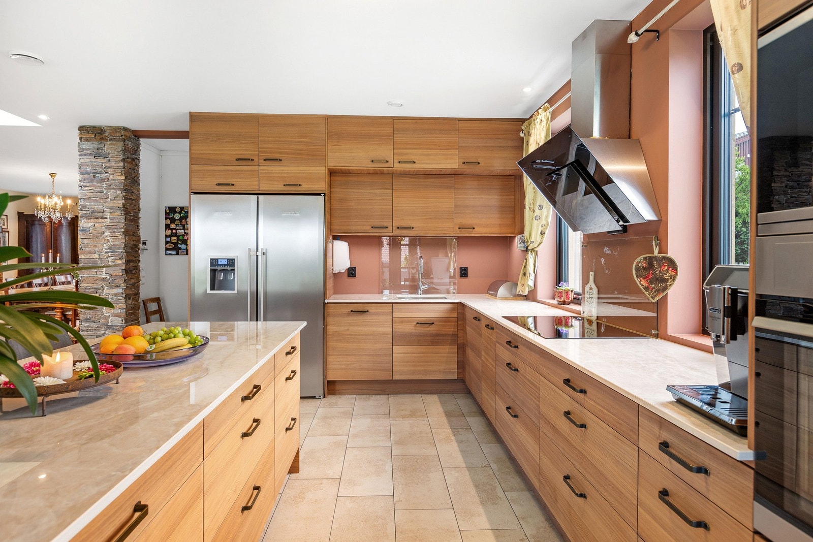 Innholdsrikt kjøkken med integrerte hvitevarer som kjøl-/frys, oppvaskmaskin, induksjonstopp, mikrobølgeovn og stekeovn. Galleribilde