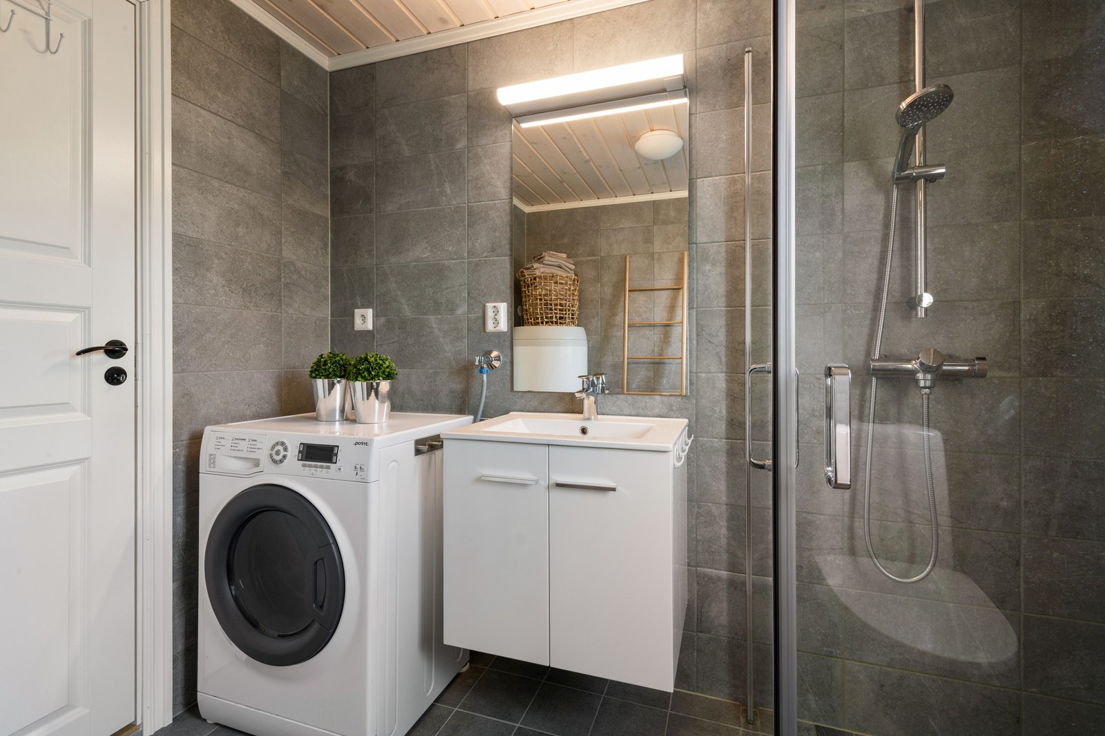 Badet er innredet med toalett, dusj, servant med innredning og opplegg for vaskemaskin. Galleribilde