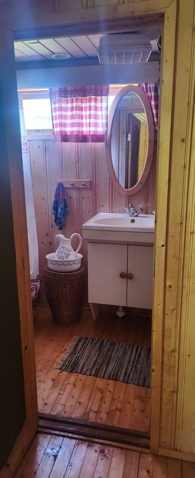 Bad utstyrt med et dusjkabinett som har fotpumpe, samt en servant med skap for oppbevaring. Galleribilde