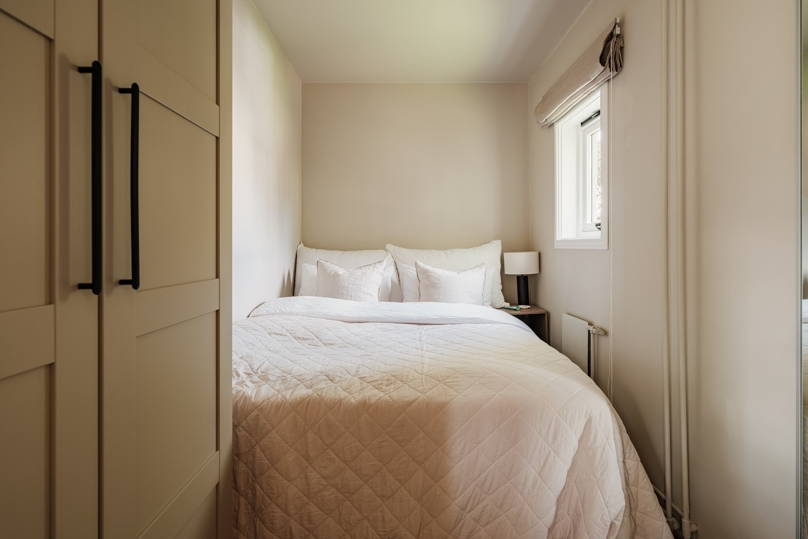 Soverommet er lunt malt i sval beigefarge, med god plass til dobbeltseng med nattbord. Galleribilde