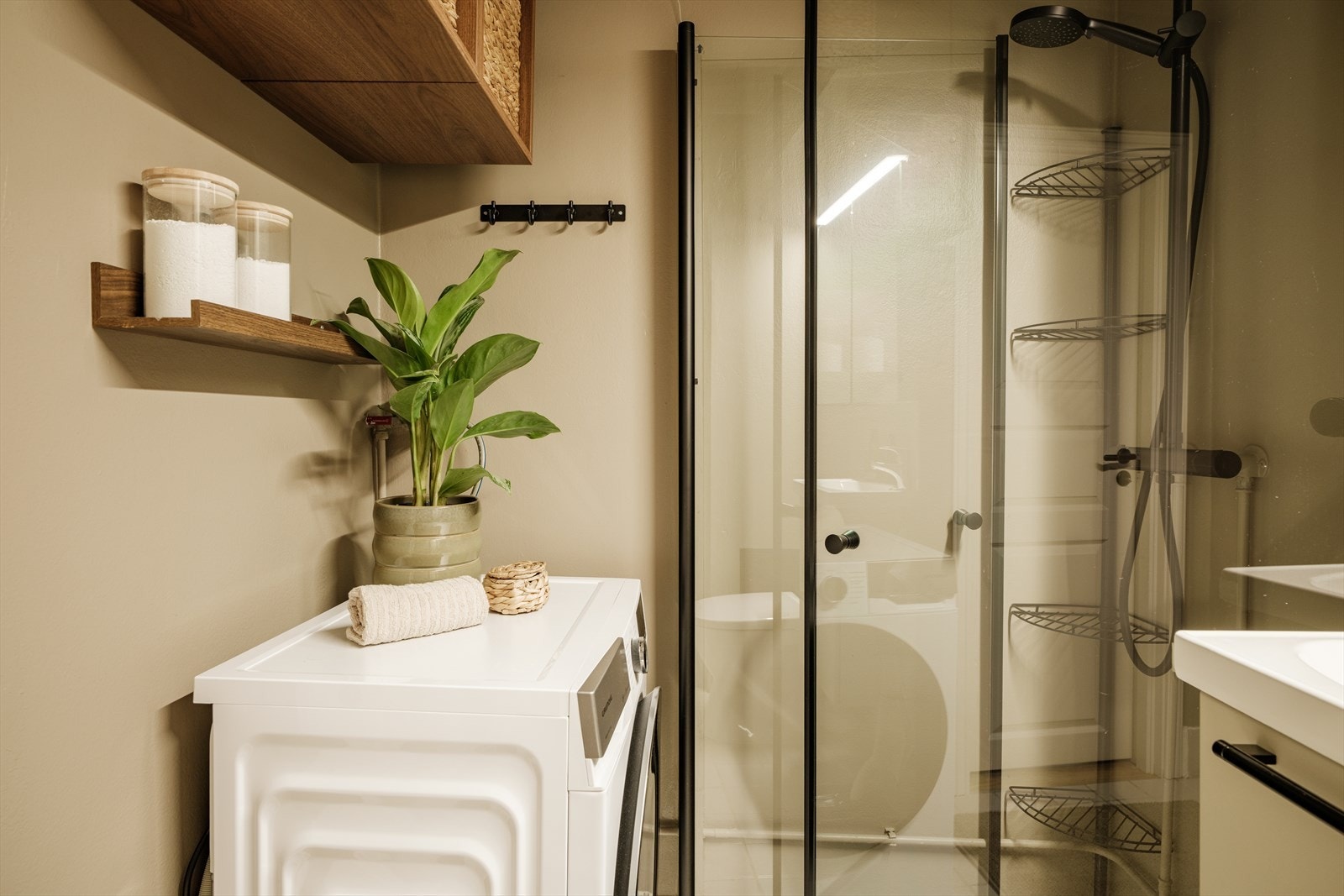 Praktisk innredning med servant i skuffeseksjon og speilskap for oppbevaring. Det er opplegg for vaskemaskin. Galleribilde