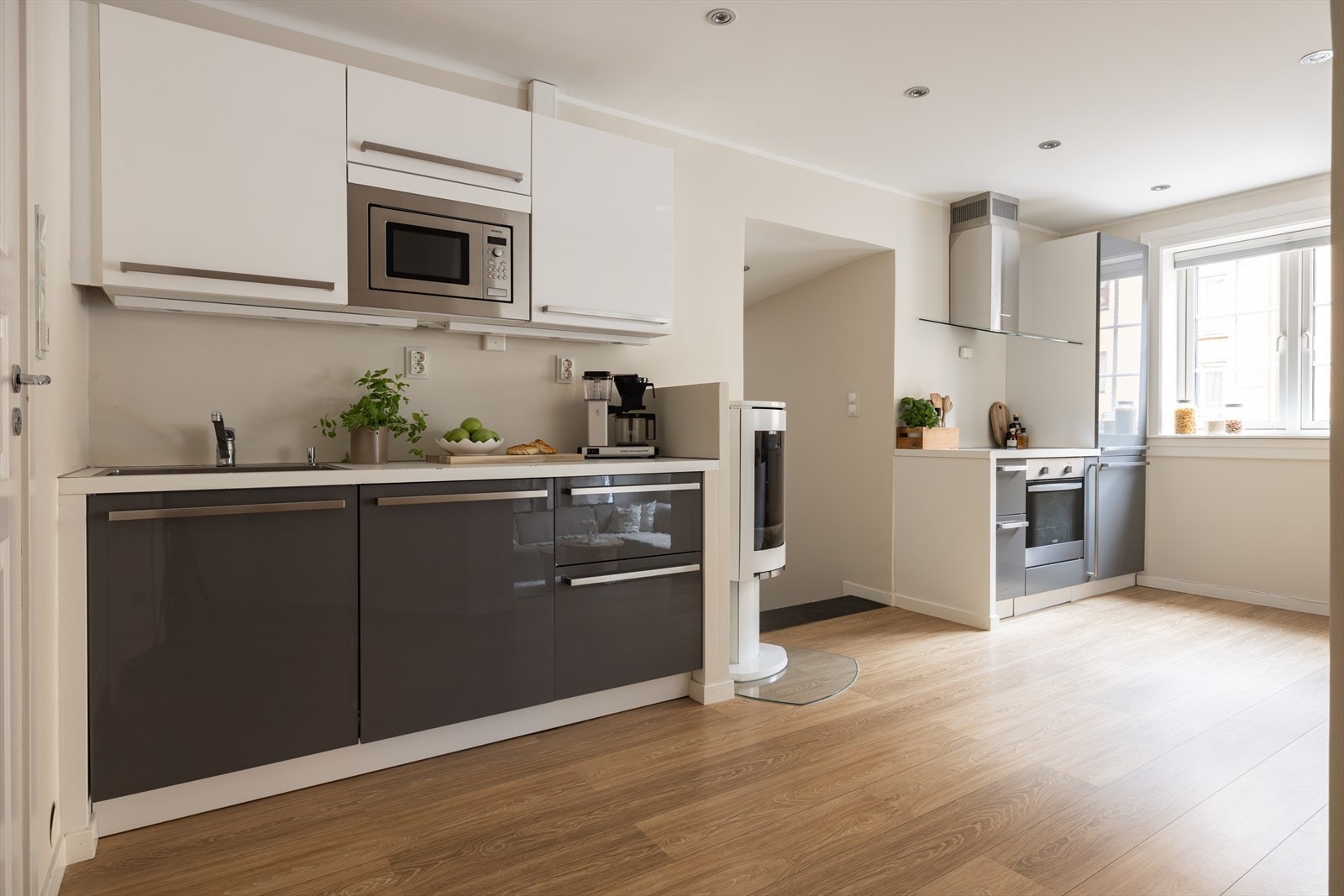 Kjøkkeninnredning med glatte fronter, laminat benkeplate, nedfelt kum samt ventilator med kullfilter Galleribilde