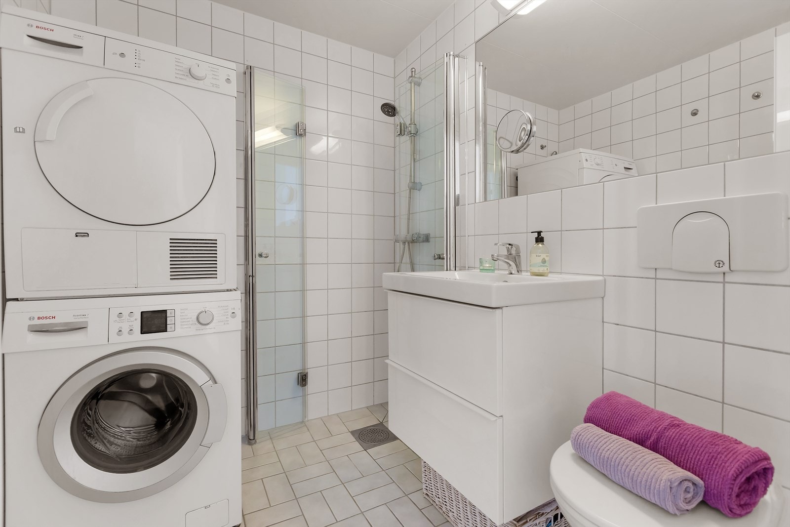 Dusjhjørne, vegghengt toalett og opplegg for vaskemaskin. Baderomsinnredning med servantskap og skuffer, samt innfelt speil med belysning over. Galleribilde