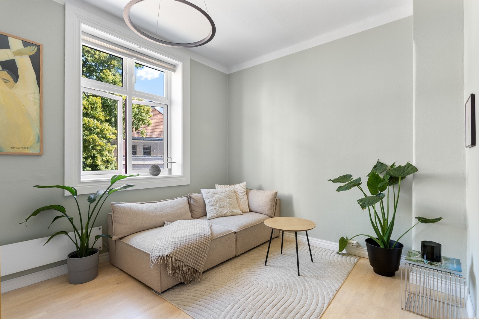 Nymalt stue med generøs takhøyde og stort vindu med grønt utsyn. Galleribilde