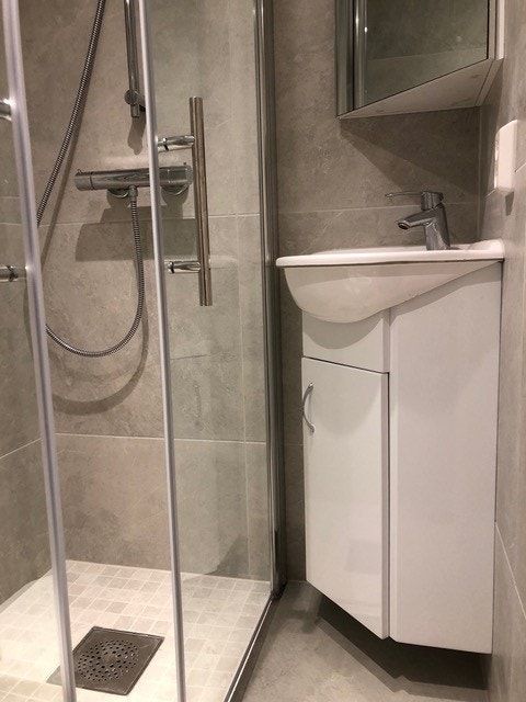 Nyere bad med dusjhjørne, servant med underskap og vegghengt toalett Galleribilde