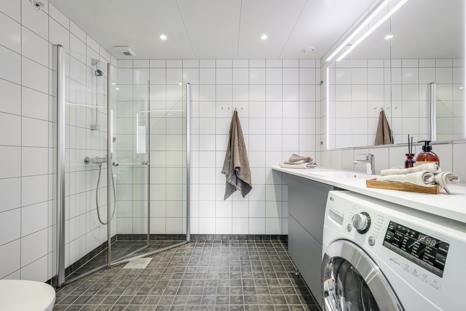 Leiligheten har et lyst og moderne flislagt baderom fra byggeåret 2016. Baderommet har mørke fliser på gulv med gulvvarme, hvite fliser på veggene, downlights i himlingen og mekanisk avtrekk. Galleribilde