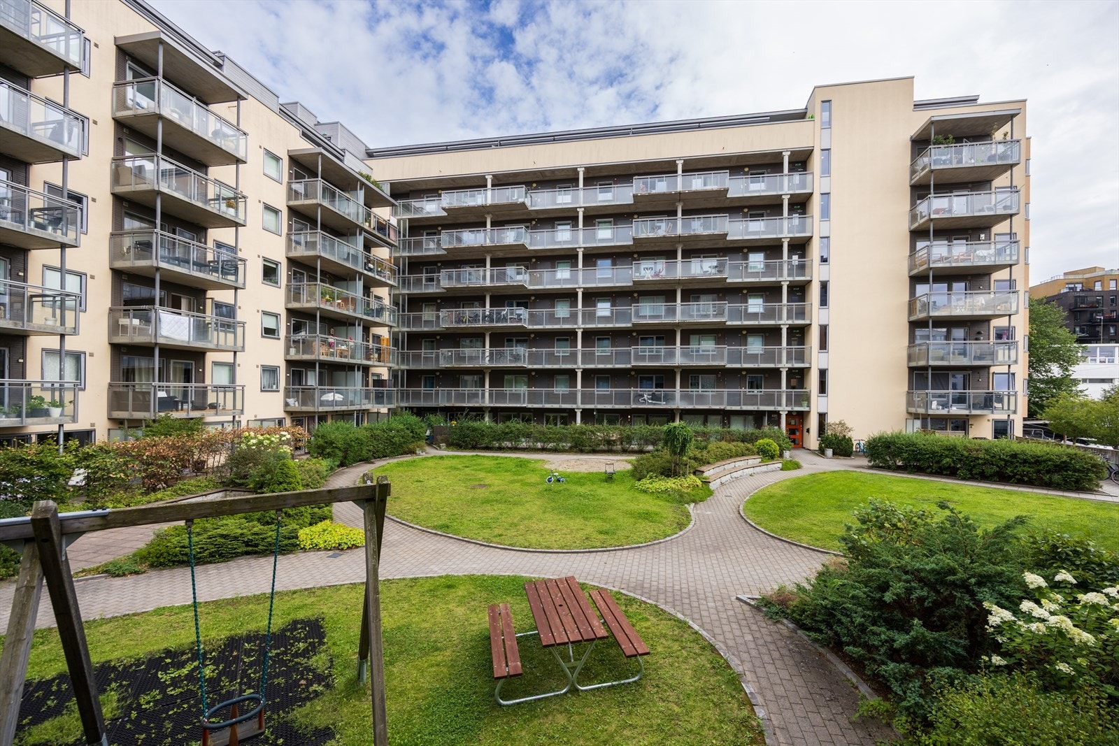 Fellesområdene i sameiet er pent opparbeidet med gressplen, prydbusker, steinlagte gangstier, lekeapparater, sittegrupper og sykkelparkering Galleribilde