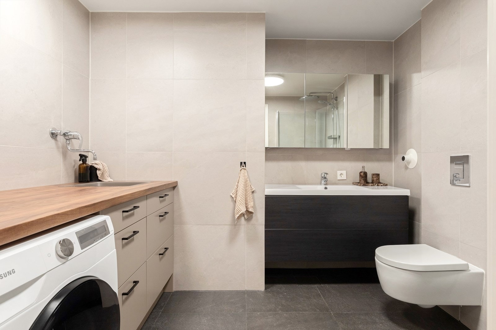 Det andre badet er av romslig størrelse og innredet med dusjhjørne, servantskap, vegghengt toalett og et praktisk område med vaskemaskin Galleribilde