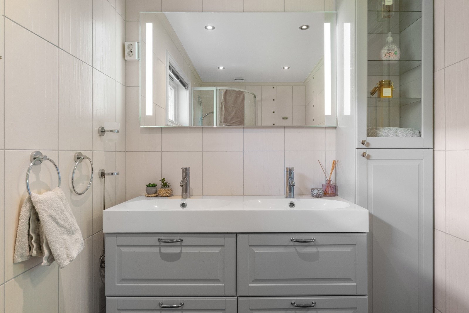 Badet er helfliset og utstyrt med foldedører i dusj, veggtoalett og baderomsinnredning med heldekkende servant. Galleribilde