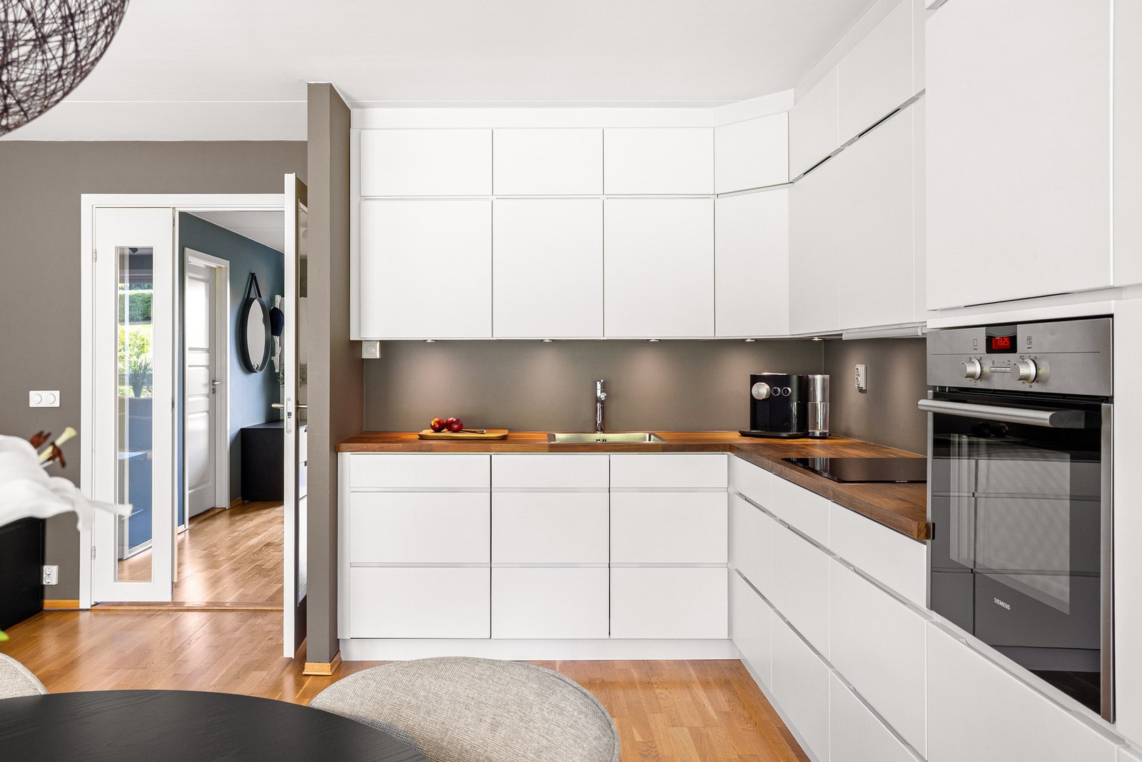 Videre er kjøkkenet utstyrt med nedfelt oppvaskkum i rustfritt stål med ett-greps kjøkkenarmatur, samt benkeskapsbelysning mellom benkeplate og overskap og stikkontakt på vegg over benkeplate. Galleribilde