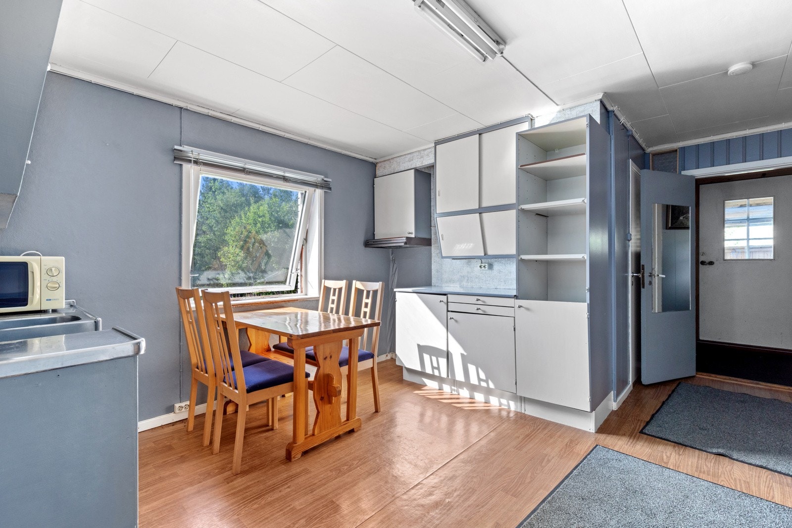 Kjøkken har innredning i heltre med foliert benkeplate og nedsenket oppvaskkum i stål Galleribilde