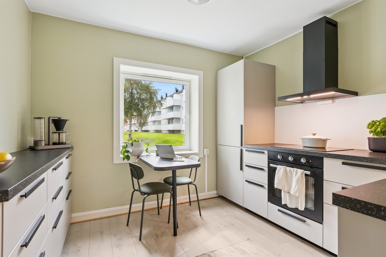 Et kjøkken som er tidsriktig med en moderne beige farge på innredningen, med sorte detaljer. Her har selger bygget et spisebord i samme materialet som benkeplaten - rett og slett gjennomtenkt! Galleribilde