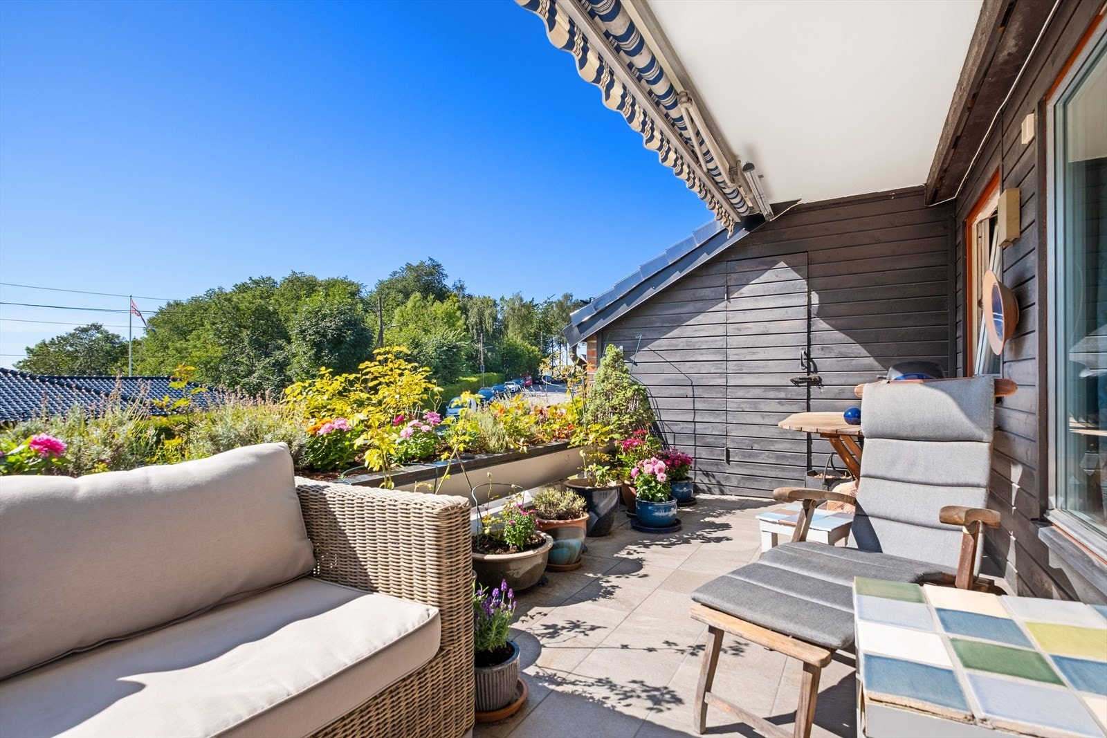 Lun og solrik terrasse med frodig beplantning og hyggelig utsikt - perfekt sted for morgenkaffen eller de sene sommerkveldene Galleribilde