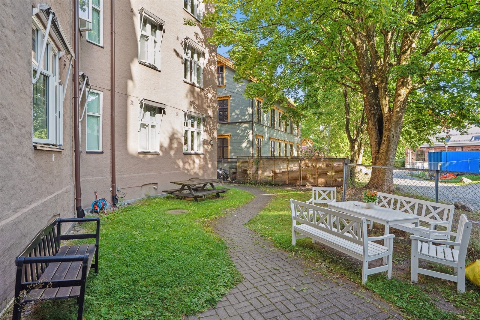 Hyggelig bakgård i borettslaget bestående blant annet av sittegrupper, trær og planter. Galleribilde