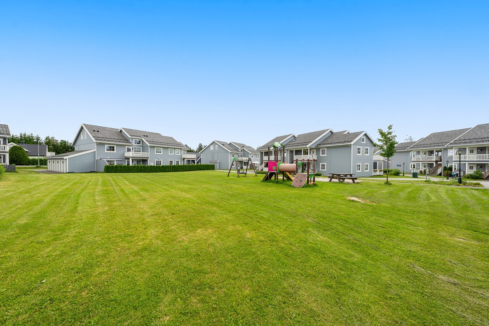 Sameiets fellesområder er pent opparbeidet med gjesteparkering, carporter, gressplen, lekeplass og noe beplantning Galleribilde