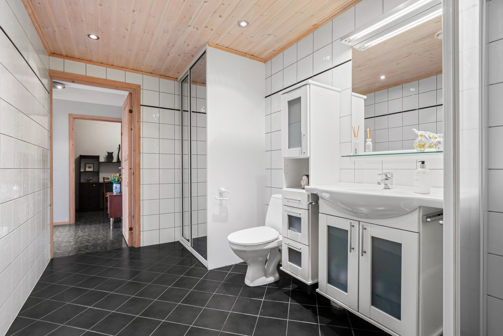 Innredningen har hvite, profilerte fronter og består av en heldekkende servant på en skapseksjon. I en smart skyvedørsløsning er det opplegg og plass for vaskemaskin. Galleribilde