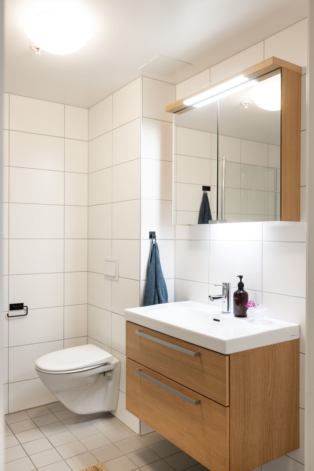 Badet er innredet med vegghengt klosett, servant nedfelt i innredning, speilskap m/lys og dusjhjørne med svingbare glassdører. Galleribilde