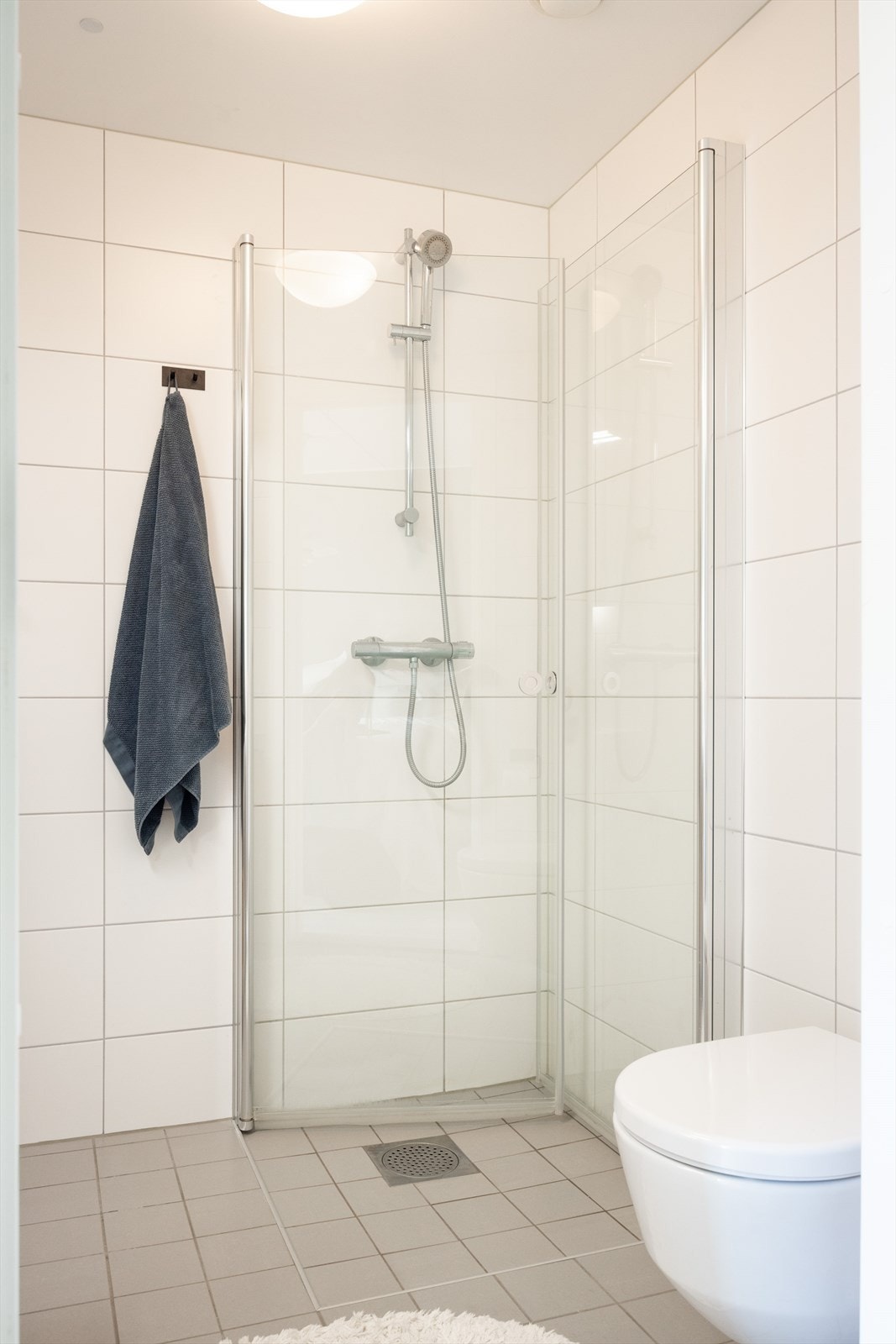 Badet er innredet med vegghengt klosett, servant nedfelt i innredning, speilskap m/lys og dusjhjørne med svingbare glassdører. Galleribilde