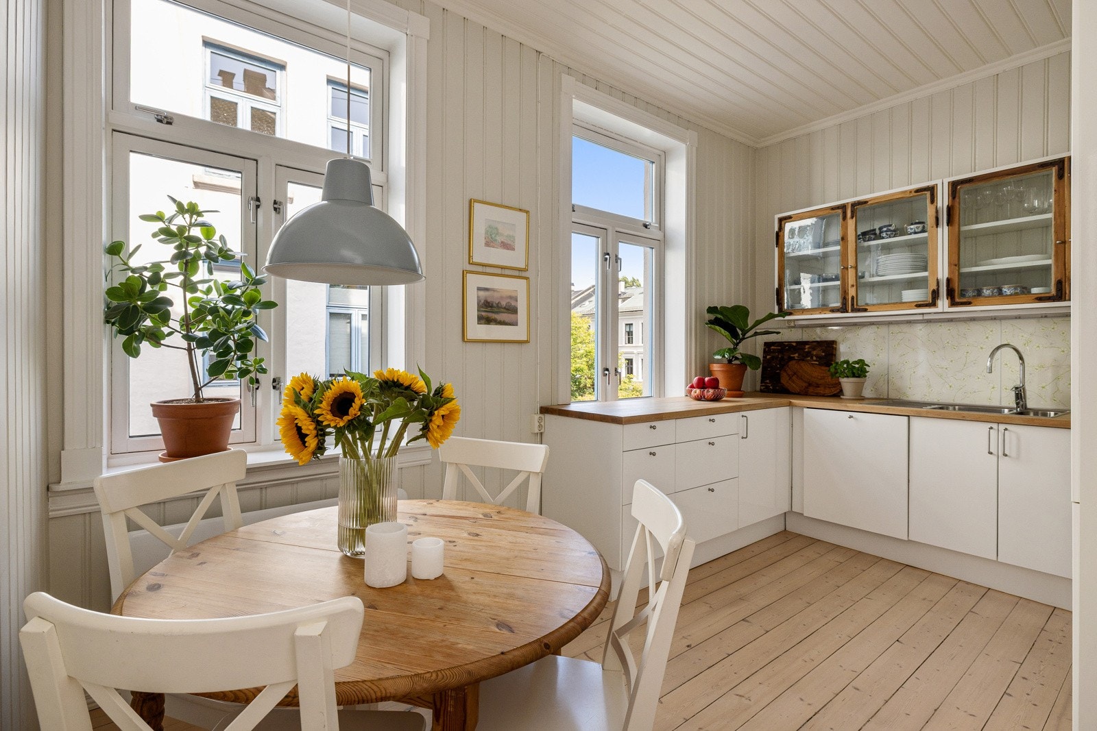 Lyst og pent kjøkken med hvit innredning og heltre benkeplate. Galleribilde