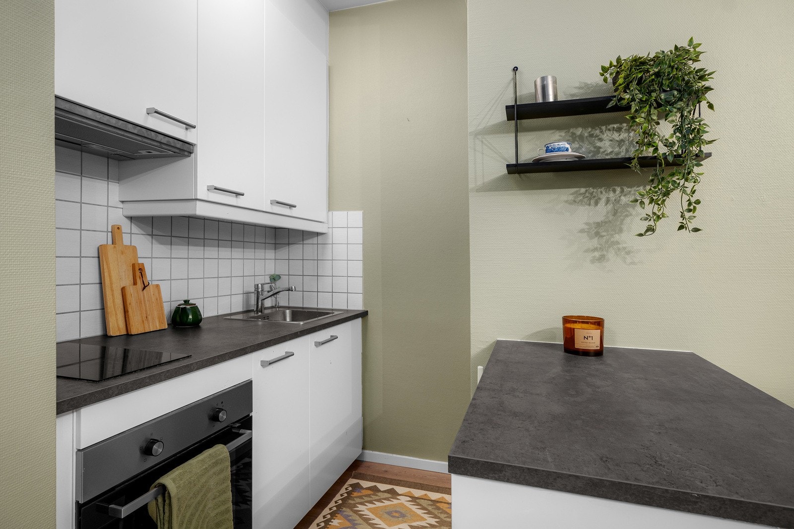 Kjøkkenet er innredet med glatte fronter, laminat benkeplate, fliser på vegg over benk og lys under overskap. Galleribilde