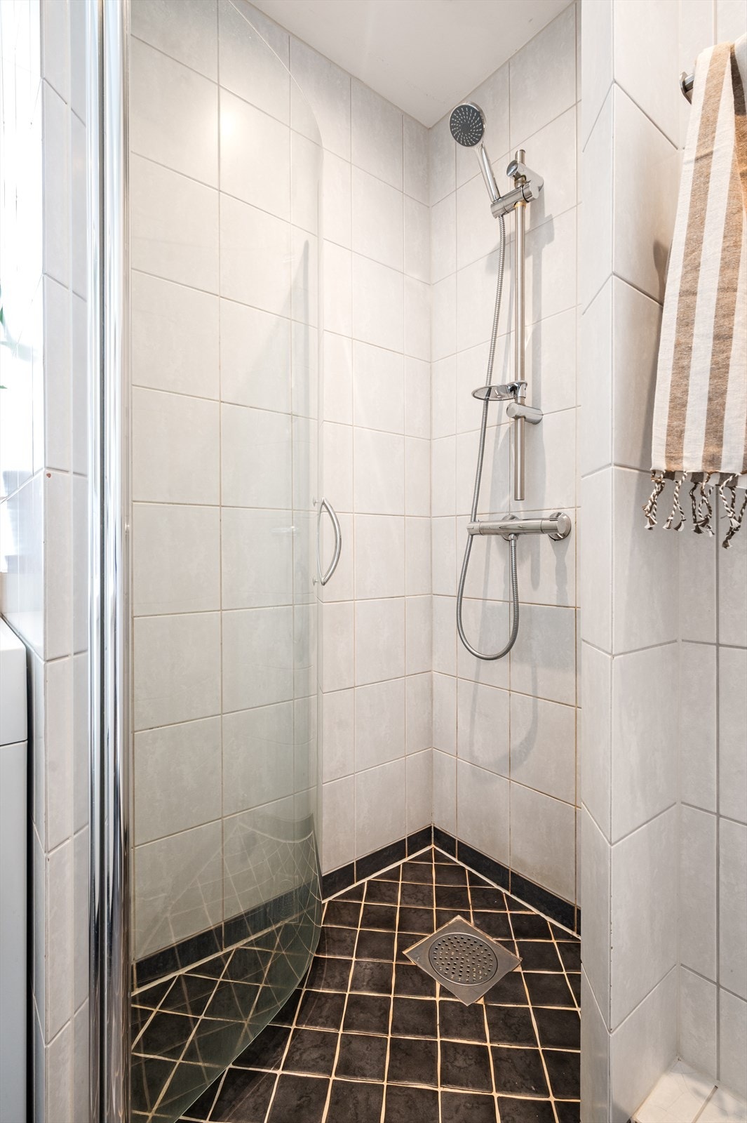 Dusjhjørne av murte vegger og innfellbar buet dusjdør av glass, dusjarmatur og dusjgarnityr. Galleribilde