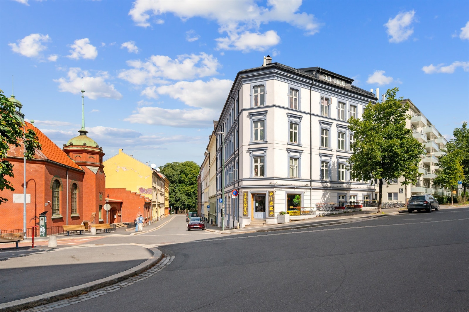 Hyggelig gatemiljø utenfor med brede fortau, syrintrær og lite trafikk. Galleribilde