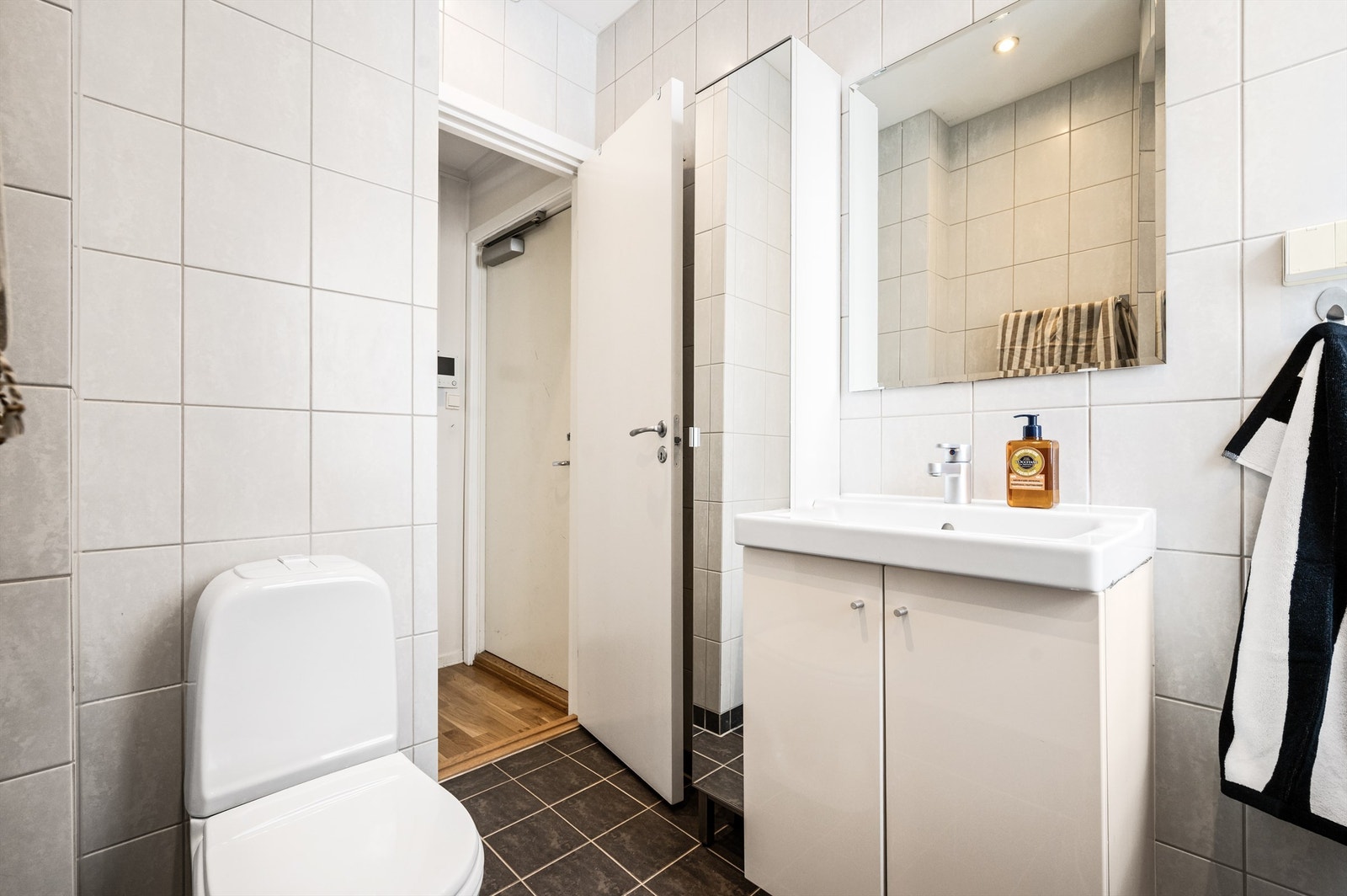 Badet har veggmontert skap med speildør for ytterlig oppbevaringsplass. Videre er badet innredet med og gulvmontert toalett. Opplegg for vaskemaskin. Galleribilde