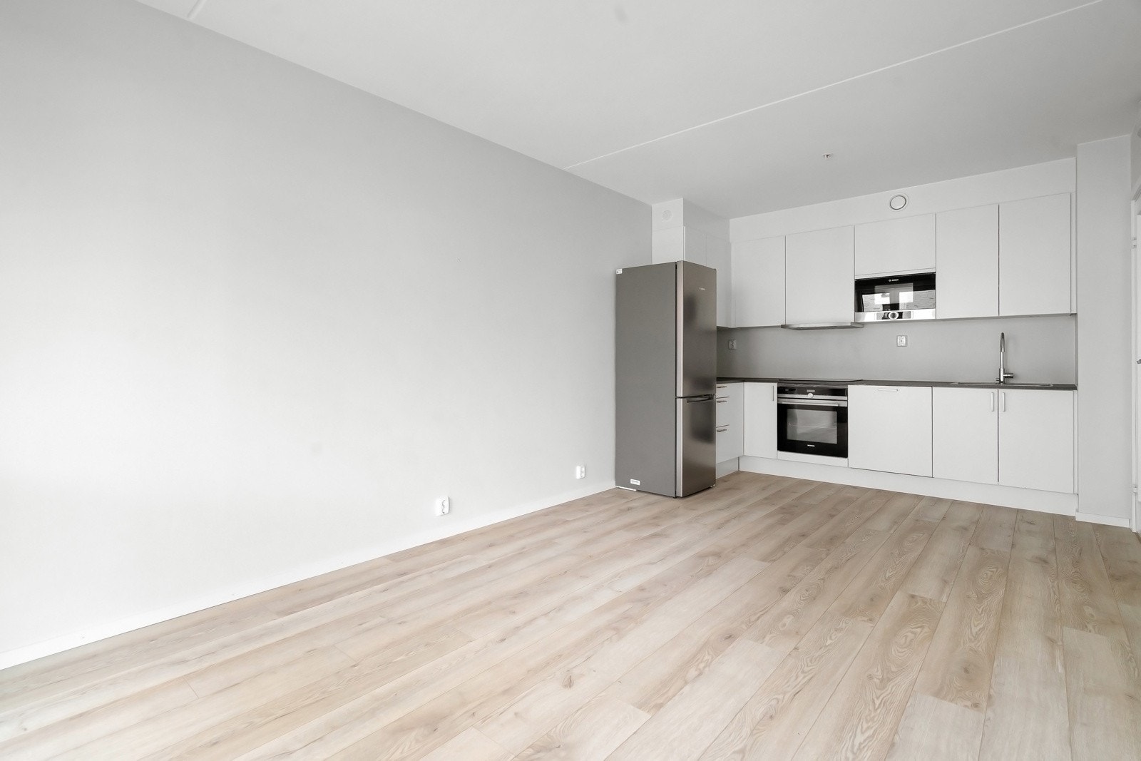 I en åpen løsning mot stuen finner du et stilrent og delikat kjøkken med glatte fronter og benkeplate av laminat. Galleribilde