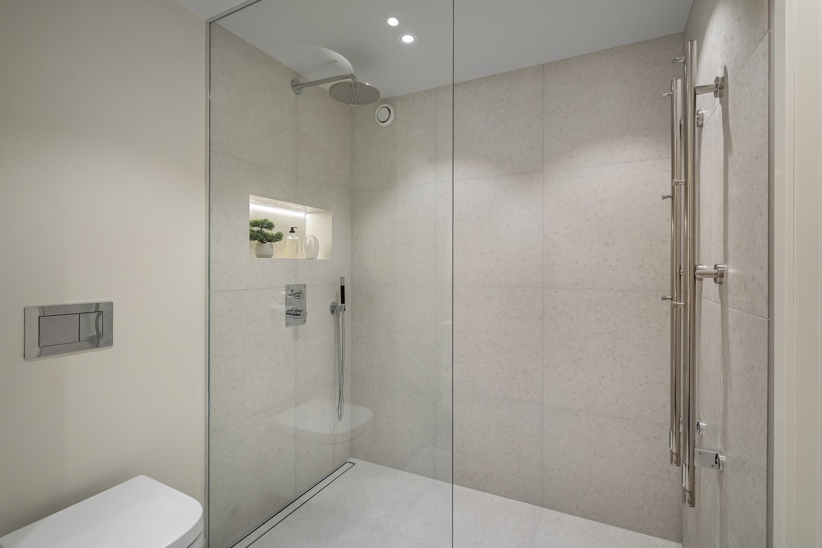 Dusjnisje utstyrt med skreddersydd glassvegg, innfelt hylle med lys og både regnfallsdusj og hånddusj Galleribilde