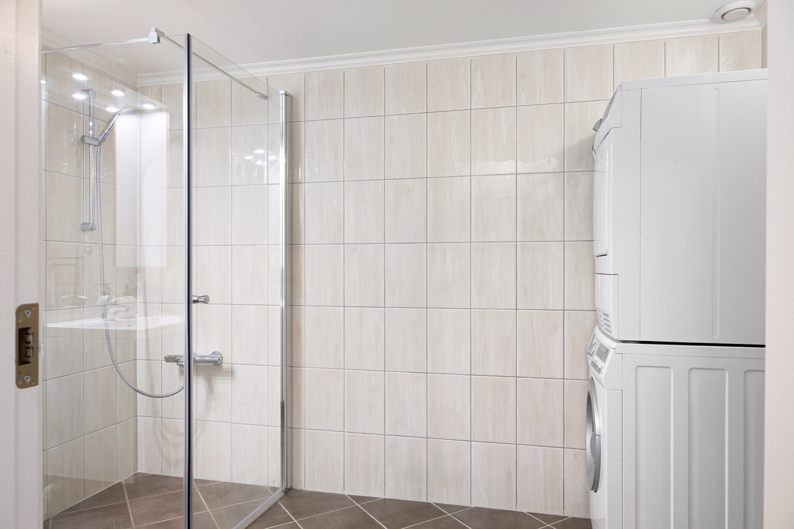 Badet er helfliset og utstyrt med gulvvarme, dusjhjørne, speil med belysning og servant i underskap. Her er det også opplegg for både vaskemaskin og tørketrommel. Galleribilde
