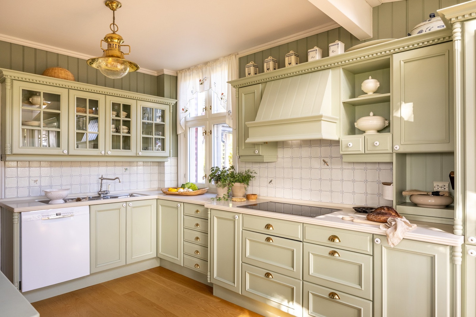 Kjøkkeninnredning med grønne profilerte malte fronter, vitrineskap og profilert belistning/ornamentering. Galleribilde