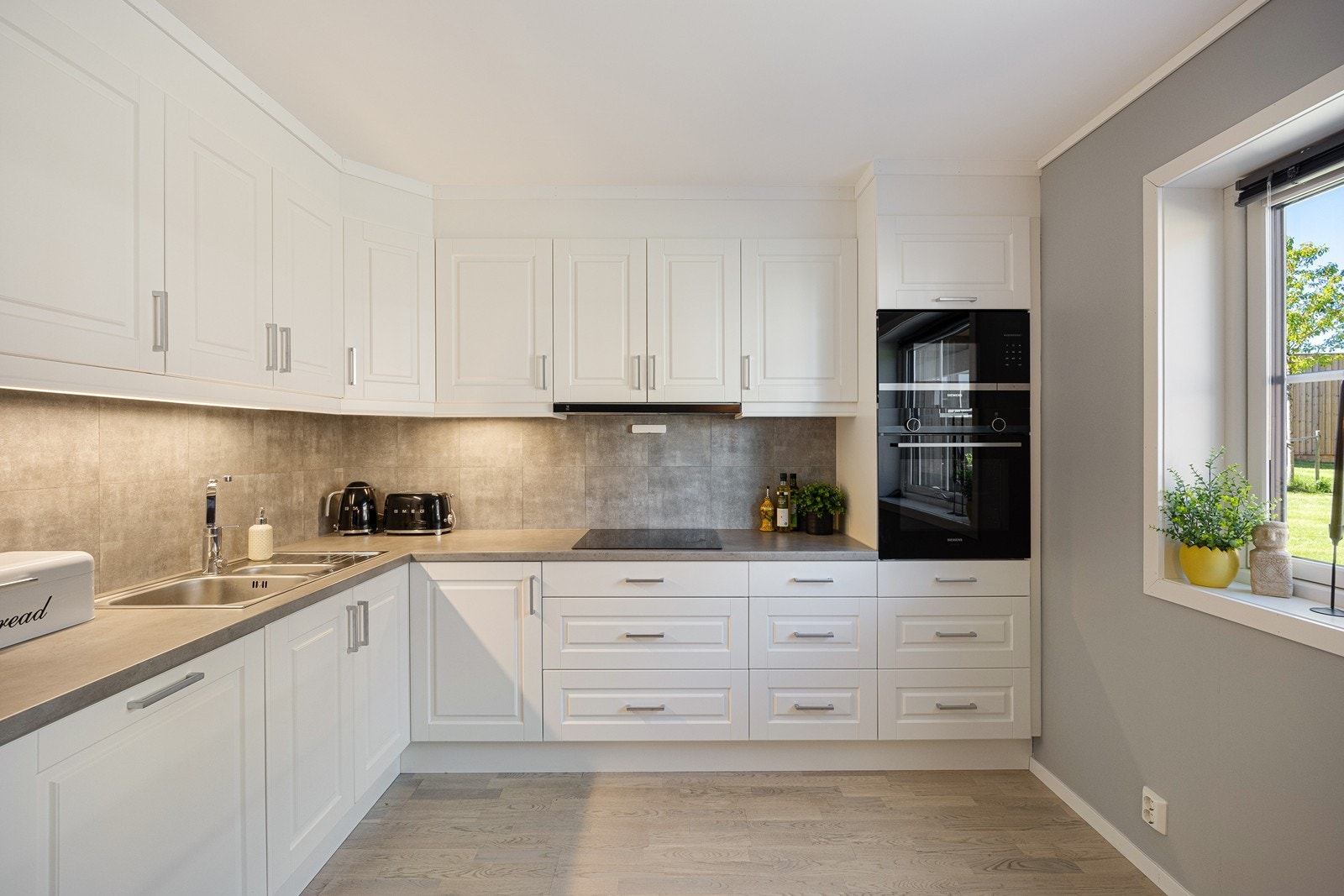 Den takoppbygde innredningen har hvite, profilerte fronter, benkeplate av laminat, benkebelysning, samt nedfelt skylle- og oppvaskkum. Galleribilde
