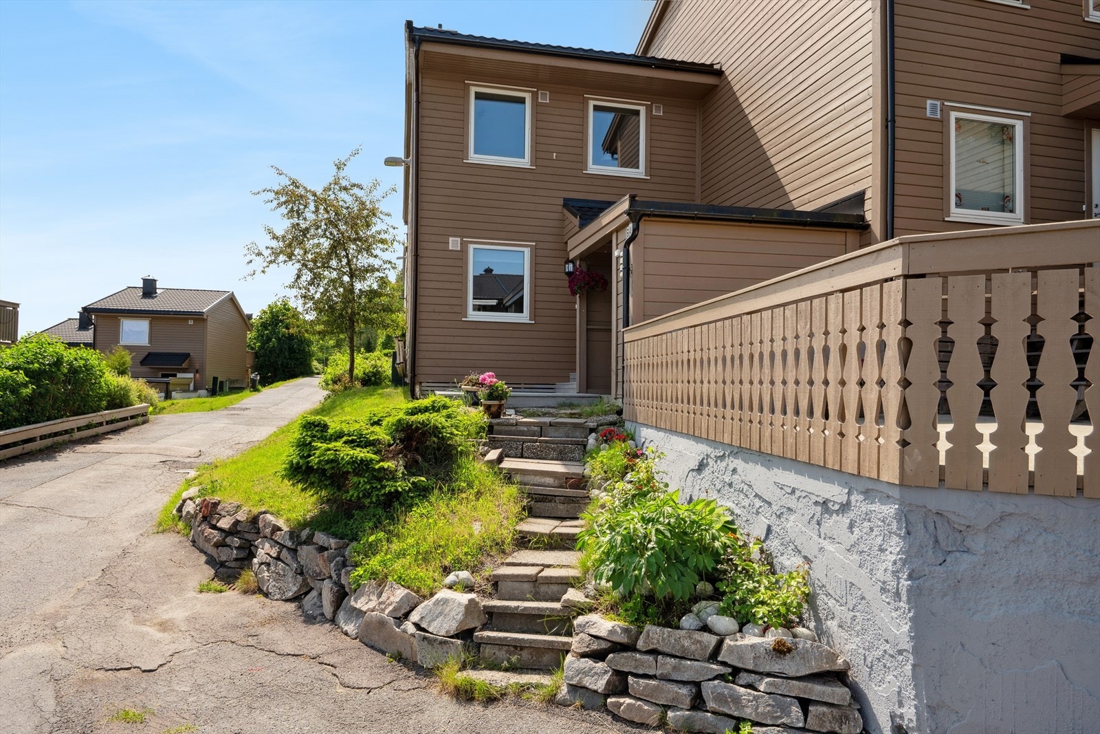 Eiendommen ligger i relativt skrånende terreng og tomten er opparbeidet med steintrapp, støttemur, gressplen, steinbedd med roser og pioner . Parkering i felles garasjeanlegg. Galleribilde