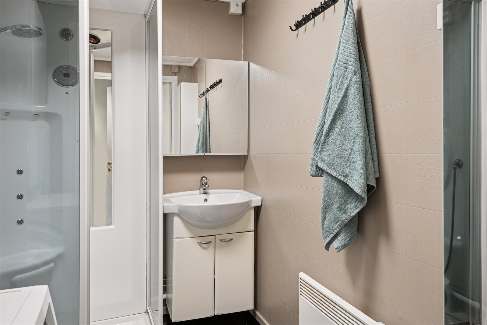 Baderommet har vinylbelegg på gulv og malte plater på vegger, utstyrt med dusjkabinett, baderomsinnredning med servant, speilskap, samt opplegg for vaskemaskin. Det er elektrisk styrt vifte. Galleribilde