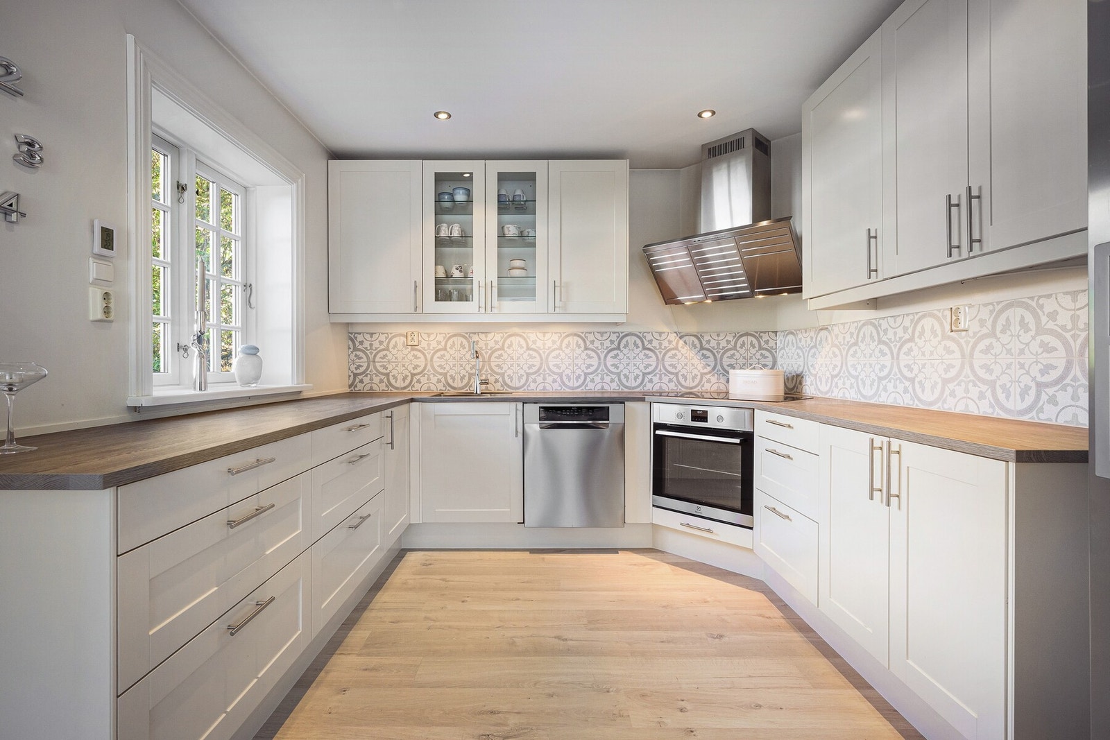 Kjøkkenet har en tidløs og funksjonell utforming med god benkeplass og skapplass. Lyse fronter kombinert med dekorative fliser gir kjøkkenet et stilfullt preg Galleribilde