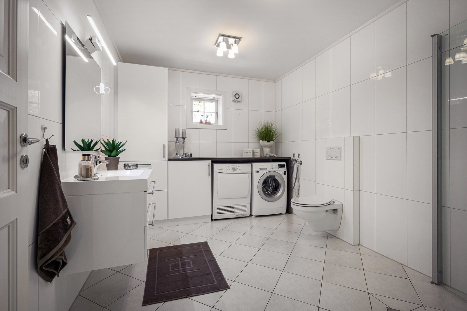 Stilrent og moderne bad innredet med dusjhjørne. Foreligger løsning for vaskemaskin og tørketrommel. Galleribilde