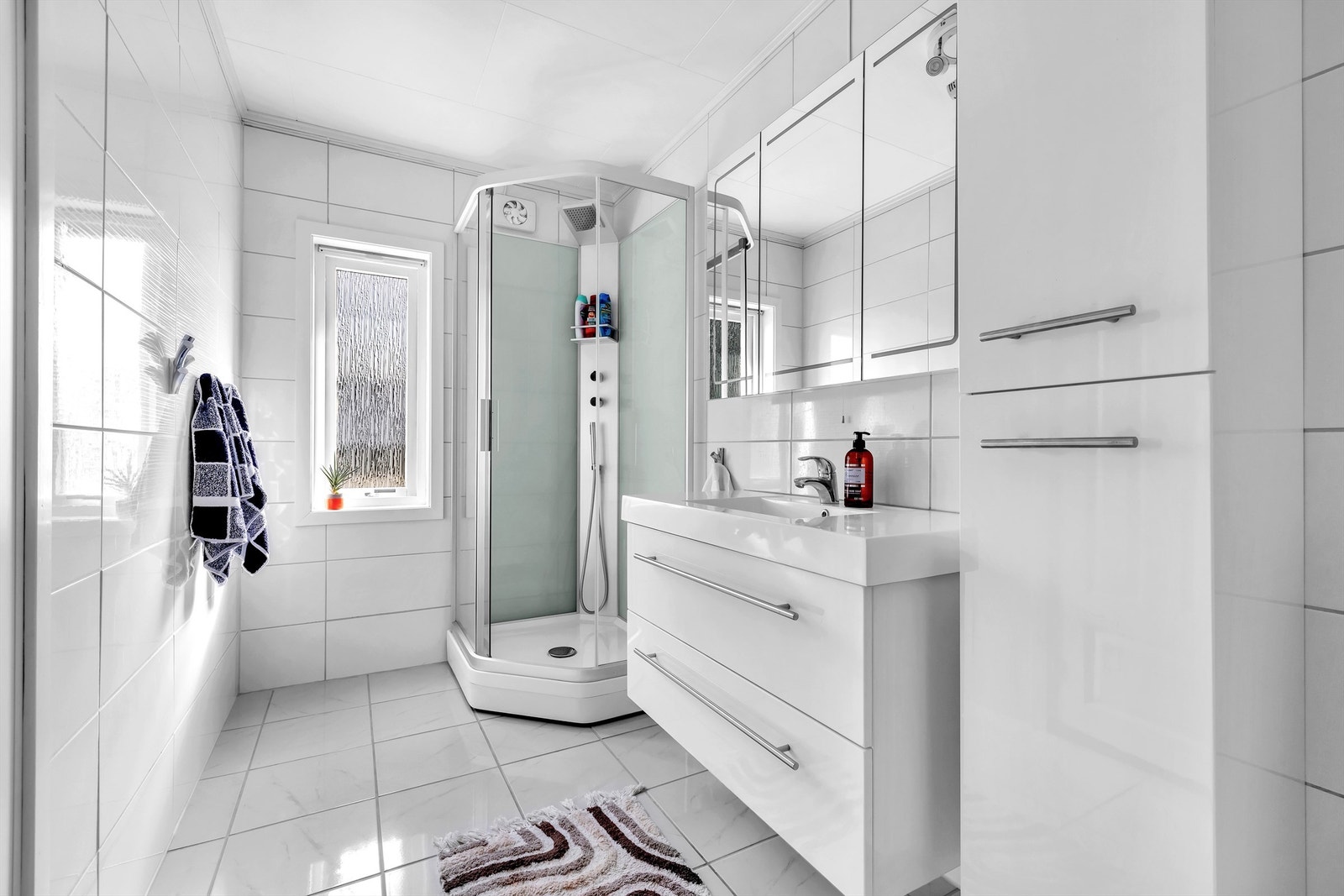 Flislagt baderom beliggende i tilknytning til soverommet i hovedetasjen, utstyrt med varme i gulv, og klassisk, vegghengt servantskap med skuffer i glatt utførelse med plass til oppbevaring av toalettartikler. Galleribilde