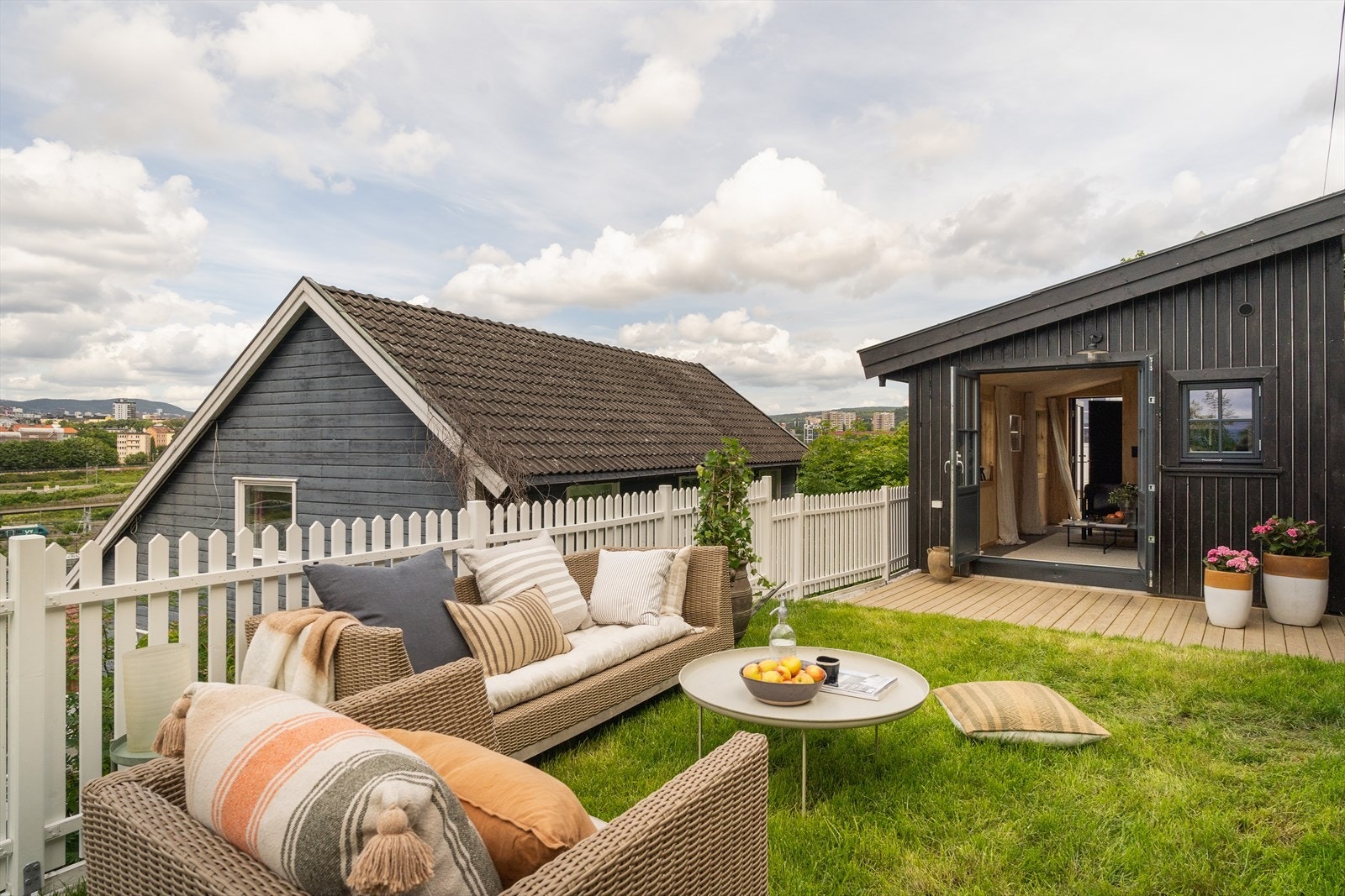 Terrassen er på begge sider av uthuset og blir forlenget med en grønn hage Galleribilde